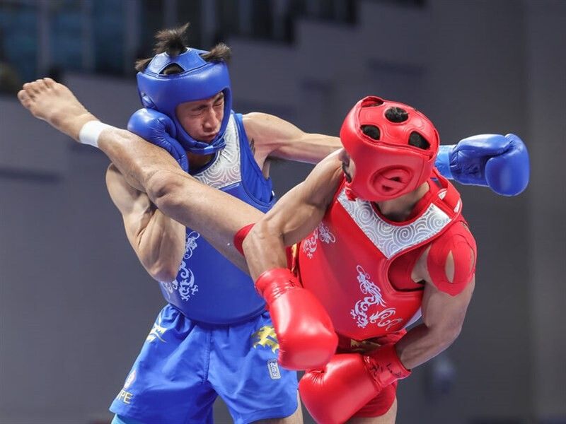 Dos competidores de sanda con casco, uno lanzando una patada